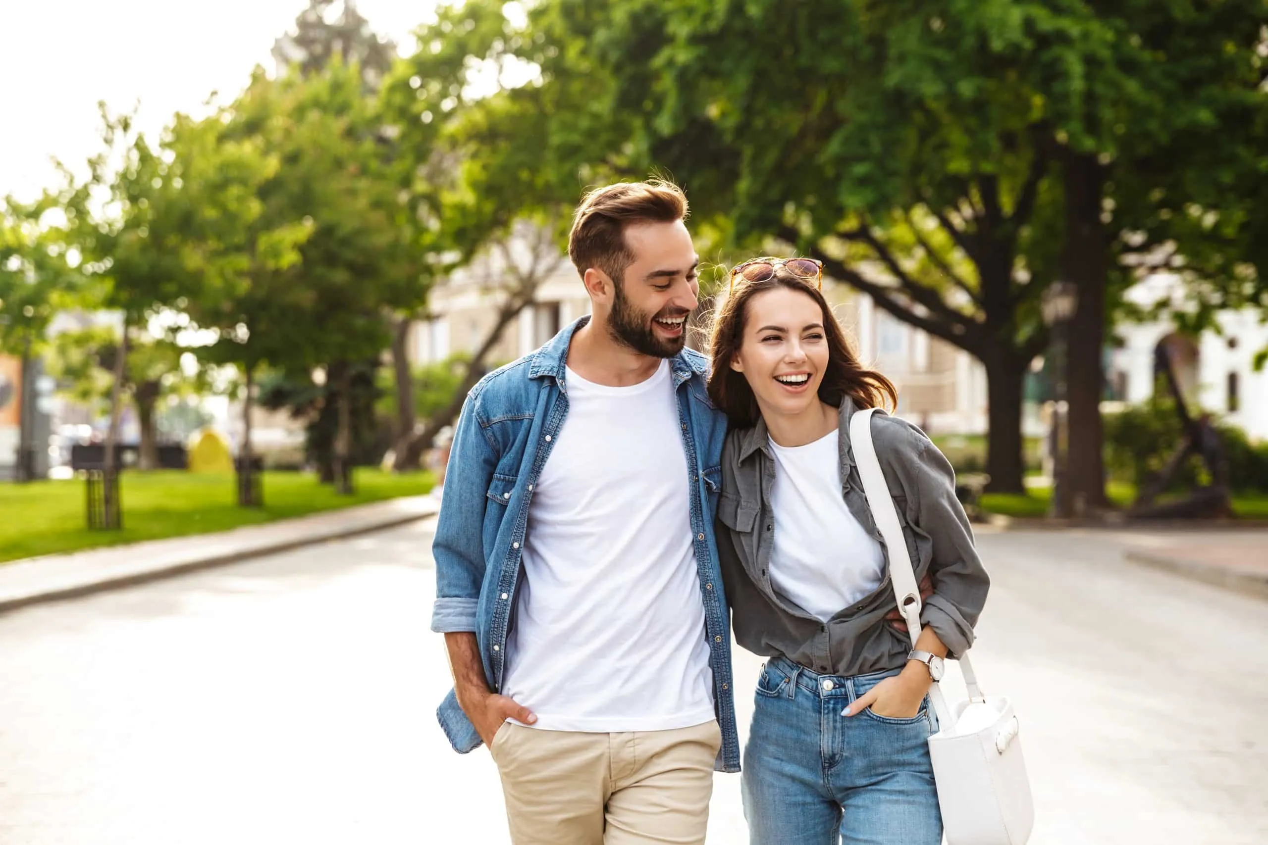 Young Gen Z Couple smiling and walking together down a street.