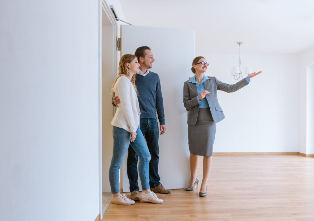 A young man and woman touring a empty home with a female real estate agent.