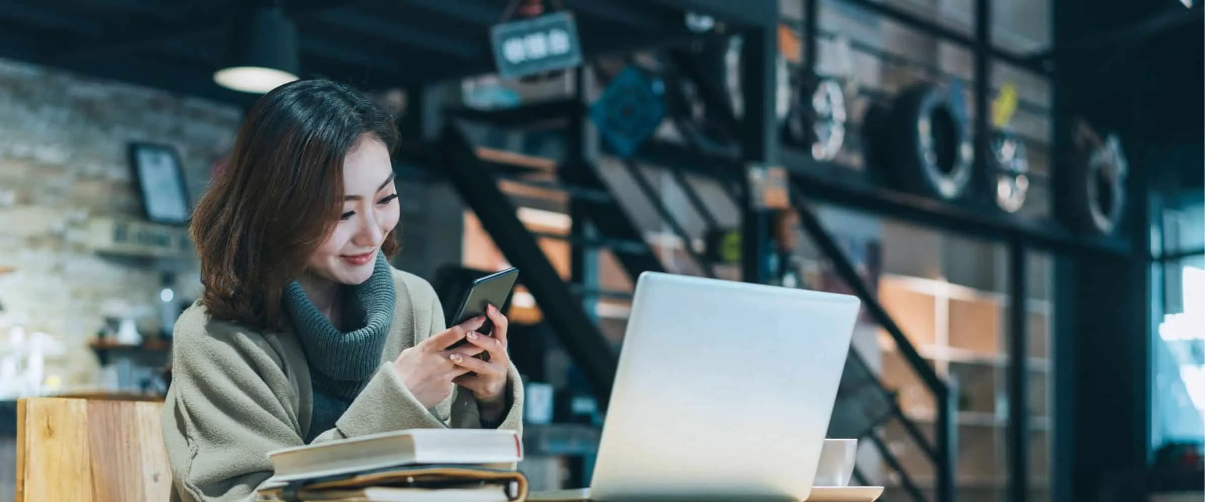 Woman sitting in coffee shop using her phone to open an account online